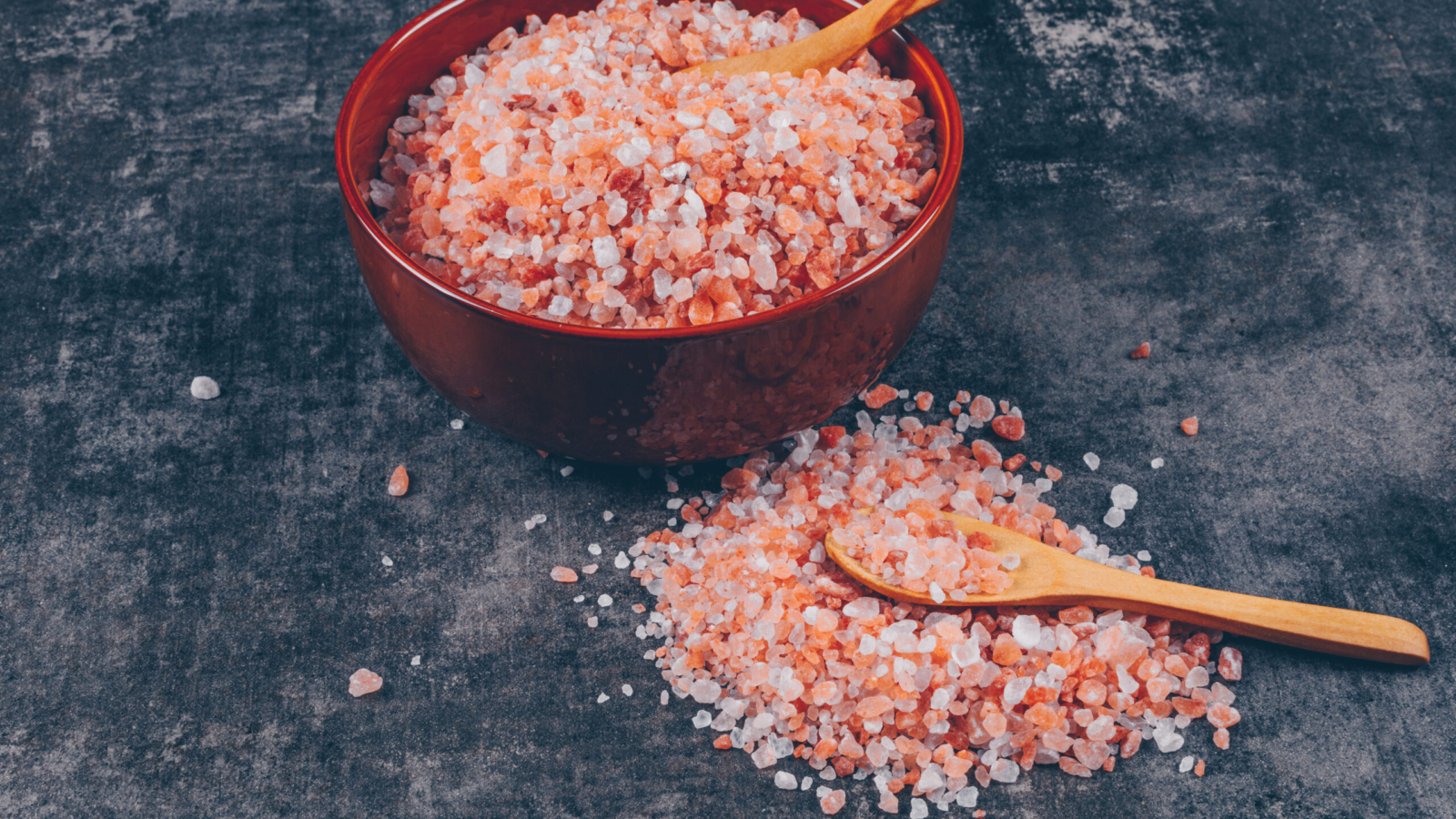High angle view himalayan salt in bowl with spoons on dark textured background. horizontal