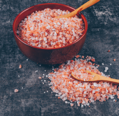 High angle view himalayan salt in bowl with spoons on dark textured background. horizontal