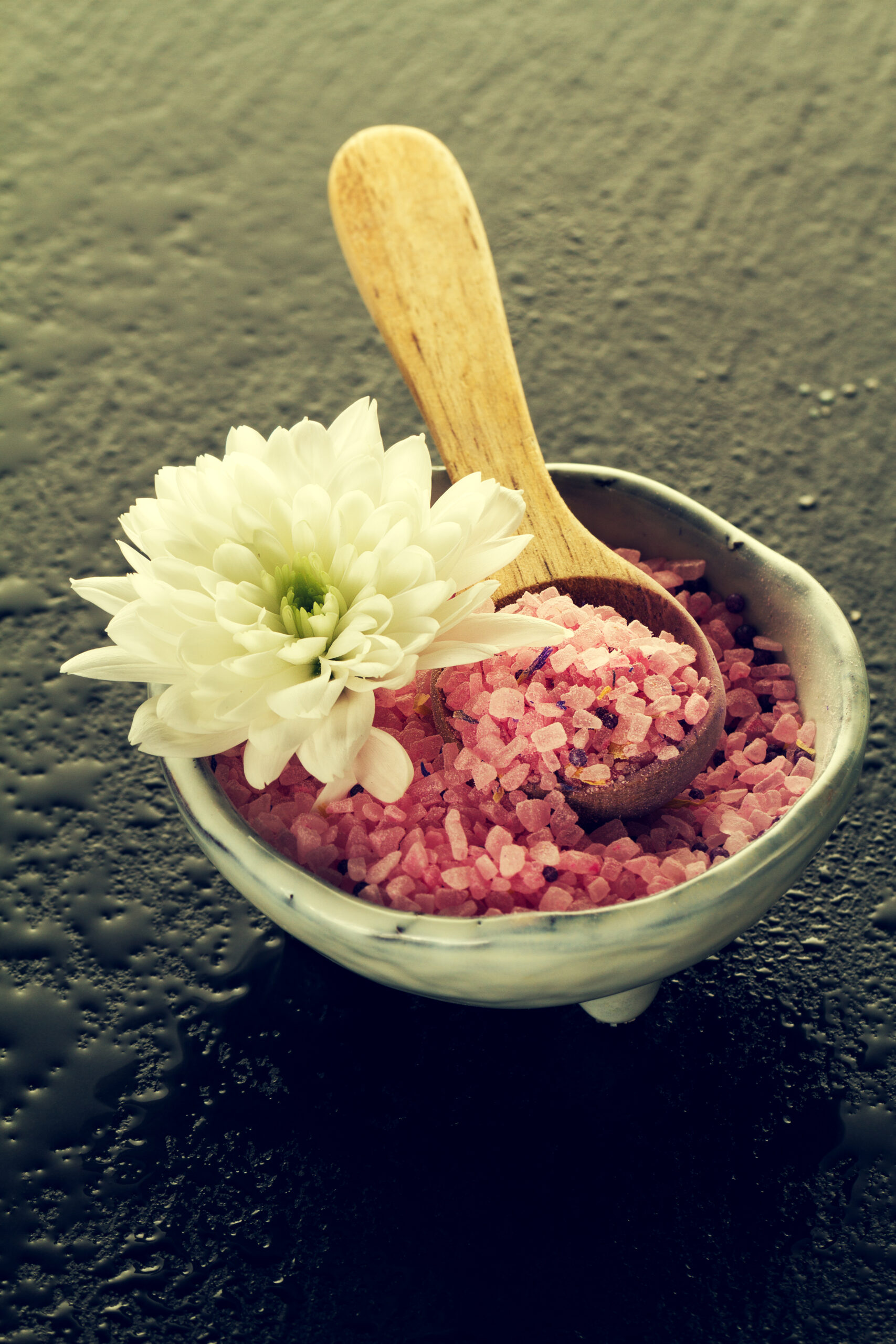 Spa Concept. Closeup of beautiful Spa Products. Spa Salt with Beautiful Flower on Dark Background.